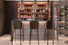 two bar stools in front of a counter with bottles on it