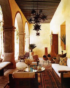 a living room filled with lots of furniture next to a tall ceiling light hanging from the ceiling