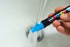 a person is holding a blue and black pipe with water coming out of it in the sink