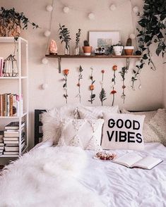 a white bed topped with lots of pillows next to a book shelf filled with books