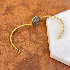 24KT yellow gold-plated + sterling silver replica Roman coin bangle with diamond. Double-sided silver coin set with textured, matte finish to the gold bangle! Length: 7" approx. Diameter: 60mm Band width: 2mm Weight: 11.80 grams (1) .01 CT natural, round diamond 21mm round replica coin Hook style clasp 925 sterling silver purity with 24KT gold plating Gold Bracelet With Oxidized Finish As A Gift, Yellow Gold Metal Cuff Bracelet, Gold Cuff Bracelet With Oxidized Finish Gift, Gold Oxidized Finish Cuff Bracelet Gift, Gold Bangle With Oxidized Finish As Gift, Gold Bangle With Oxidized Finish For Gift, Yellow Gold Brass Cuff Bracelet, Adjustable Engraved Coin Jewelry, Engraved Adjustable Coin Jewelry