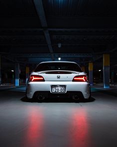 the back end of a white car in a parking garage