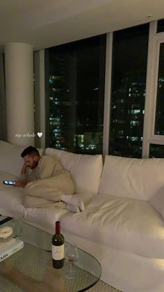 a man sitting on a couch with a bottle of wine in front of his face