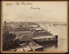 an old black and white photo of a town by the water with kites flying in the sky