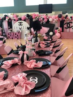 a table set up for a baby shower with pink and black plates, napkins, and decorations