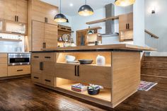 an open kitchen with wooden cabinets and counter tops, along with hanging lights above the island