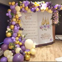 a large balloon arch is decorated with purple, gold and white balloons