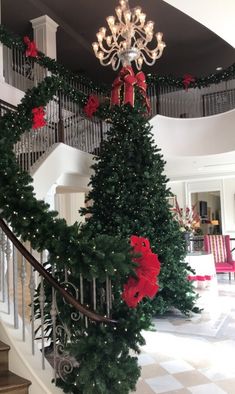 a christmas tree is decorated with red bows and poinsettis on the stairs