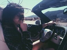 a woman sitting in the driver's seat of a car talking on her cell phone