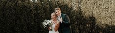 a bride and groom standing next to each other in front of some bushes with flowers