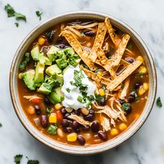 a bowl of chicken tortilla soup topped with sour cream and avocado