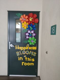 a door decorated with balloons and flowers in front of a sign that says happiness blooms in this room