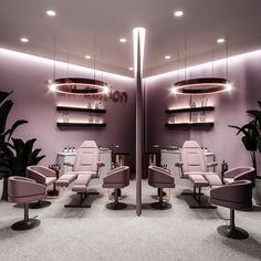 the interior of a salon with pink chairs and plants on display in front of purple walls