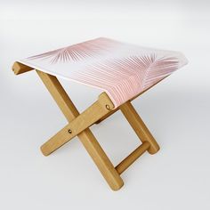 a small wooden stool with a pink and white patterned seat cover on the backrest