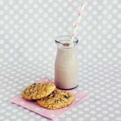 two cookies and a glass of milk on a pink napkin