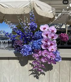 purple and blue flowers sitting on top of a wooden table next to an open umbrella