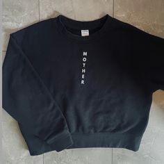 Upgrade your everyday sweatshirt with this premium crew neck in Black. Designed with a casual, yet elevated look. Created with intention and with the highest quality fabrics. Each sweatshirt has an affirmation printed on the inside tag for positive vibes all day. Wear as a daily reminder of what a strong mother you are. Fit: Sweatshirt is designed to have a shorter, more boxy fit (not cropped) Model is 5'1" and wearing a size Small Features: "Mother" printed down the front in white Color: Black Black Relaxed Fit Comfortable Sweater, Black Comfortable Relaxed Fit Sweater, Black Relaxed Fit Sweats With Letter Print, Trendy Crew Neck Sweats For Everyday, Comfortable Black Tops For Streetwear, Black Slogan Sweatshirt Crew Neck, Cotton Sweats With Letter Print For Everyday, Black Crew Neck Sweats For Everyday, Black Crew Sweats For Everyday