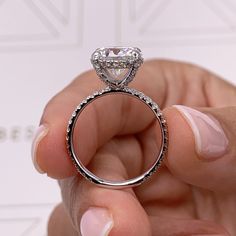 a person holding up a diamond ring in their left hand, with the center stone on it's side