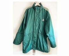 "Vintage Adidas jacket with pockets and rolled in rain hood. Would fit sizes m - l - xl, depending on desired fit Measured laying flat: 35\", 89 cm long 27\", 68.5 cm armpit to armpit 33\", 84 cm from the neck to the bottom of the sleeve Some unnoticeable colour spots, otherwise great vintage condition. If you have any questions, please let me know, I will be happy to answer! Best wishes, Juta" Sporty Raincoat For Winter Sports, Green Sporty Outdoor Raincoat, Sporty Green Raincoat For Outdoor Activities, Green Sportswear Windbreaker With Pockets, Green Casual Raincoat For Sports, Casual Green Raincoat For Sports, Sporty Green Raincoat For Sports, Green Sporty Raincoat For Sports, Functional Green Raincoat For Streetwear