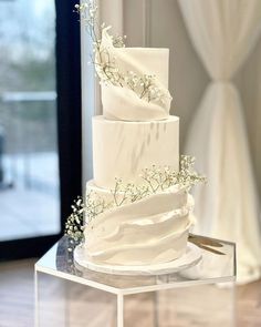 a three tiered white wedding cake with baby's breath