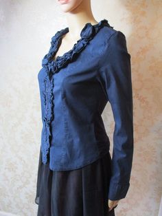 "Black long sleeved shirt with a ruffled neck line and  button band.  The back is stretchy and the front cotton.  It has buttons to close and buttons on the cuffs. Bust pit to pit flat;  19\" Length;  22\" Inside arm;  19\" Made by PORTO FORTUNA" Fitted Ruffle Blouse For Fall, Fitted Long Sleeve Blouse With Ruffles, Fitted Cotton Blouse With Ruffles, Fall Long Sleeve Blouse With Ruffles, Cotton Blouse With Ruffled Collar, Cotton Blouse With Ruffled Collar And Details, Fitted Ruffle Button-up Shirt, Chic Fitted Shirt With Ruffled Collar, Fall Blouse With Peter Pan Collar And Ruffles