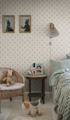 a small dog standing next to a bed in a room with two pictures on the wall