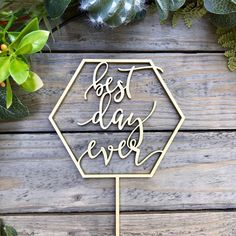 a cake topper with the words best day ever on it next to greenery