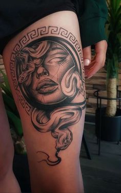 a woman's thigh with an artistic tattoo design on the leg and her face