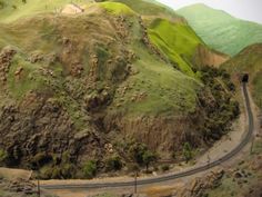 an aerial view of a mountain with a road going up it's side in the foreground