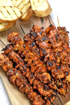 grilled chicken skewers on a cutting board with bread