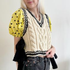 a woman with blonde hair wearing a knitted sweater and black gloves, posing for the camera