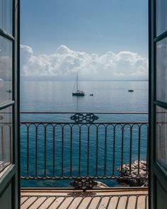 an open door leading to the ocean with boats in the water and one boat out on the water