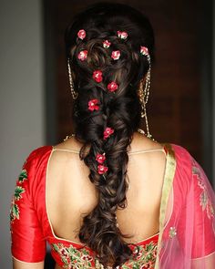 a woman with long hair wearing a red and gold sari, braided in flowers