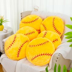 four yellow baseball pillows sitting on top of a white chair next to a potted plant