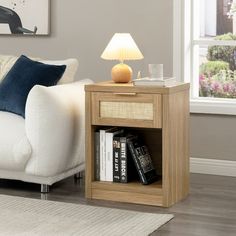 a white couch sitting next to a wooden table with books on it and a lamp