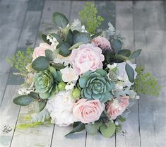 a bridal bouquet with pink roses and succulents on a wooden floor