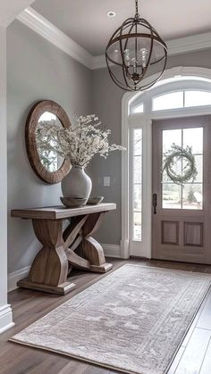 a foyer with a rug, mirror and vase on the floor in front of it