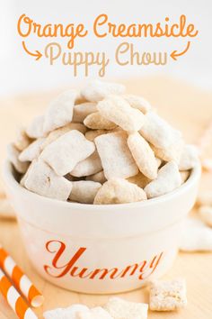 orange creamsice puppy chow is in a white bowl with candy canes on the side