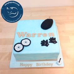 a birthday cake with blue frosting and black decorations on the top, sitting on a wooden table