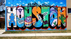 a man riding a bike past a colorful wall with the word houston painted on it