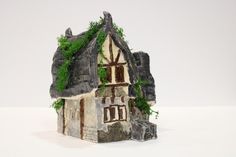 a miniature house with ivy growing on the roof and windows, in front of a white background