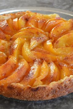 a pie with sliced peaches sitting on top of a metal pan