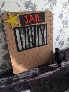 a small black dog standing in front of a jail cell with the word jail written on it