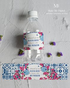 a bottle of water sitting on top of a table next to some purple and pink flowers