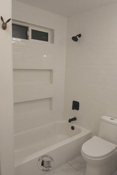 a white toilet sitting next to a bath tub in a bathroom with black and white fixtures