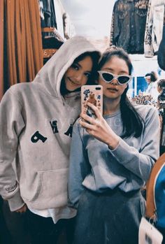 two women taking a selfie in front of clothing racks