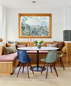 a dining room table with four chairs and a bench in front of the window,