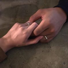 two people holding hands with wedding bands on their fingers and one is touching the other's hand