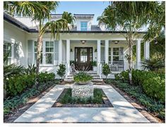 a white house with palm trees and landscaping