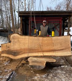 a man standing in front of a large piece of wood